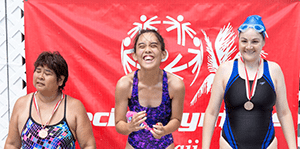Three athletes pose for a photo after winning medals in a swimming competition.